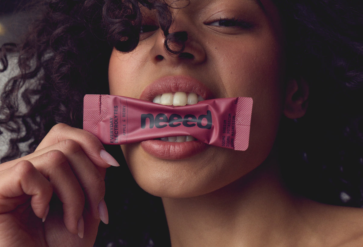 Woman biting an apple & berry neeed sachet